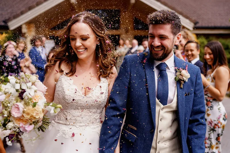Candid wedding photo of a very happy couple walking through wedding confetti by wedding photographer ARJ Photography®