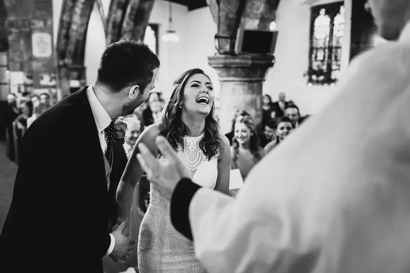 Candid wedding photo of a bride laughing during her church wedding ceremony by wedding photographer ARJ Photography®
