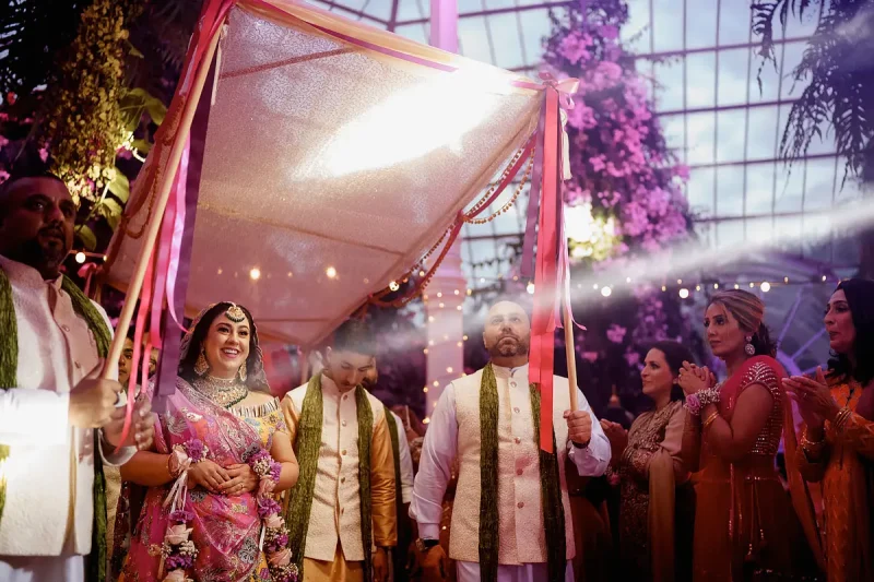 Candid wedding photo of an Indian bride entering her mehndi surrounded by family by wedding photographer ARJ Photography®