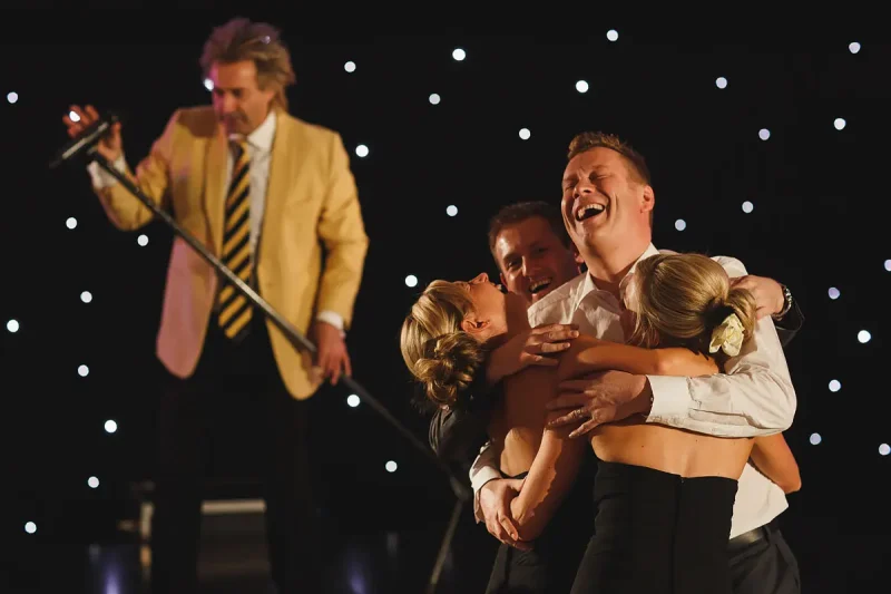 Candid wedding photo of wedding guests dancing while Rod Stewart impersonator sings during a wedding party by wedding photographer ARJ Photography®