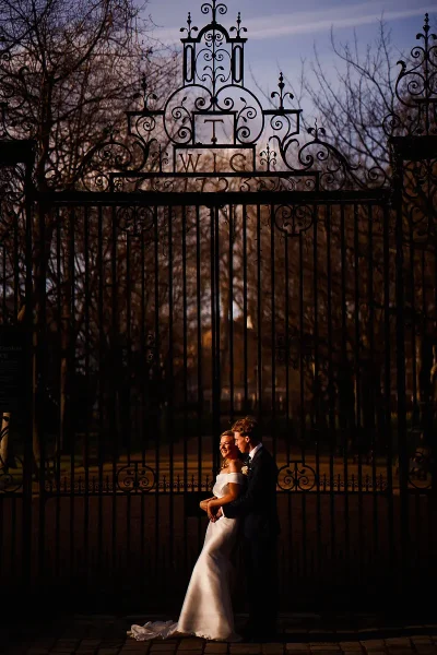 Beautifully lit wedding portrait of a bride and groom by an ornate gate at sunset during their London wedding at Gray's Inn by wedding photographer ARJ Photography®