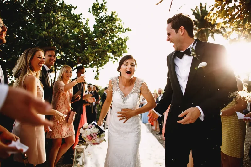 Bride laughs because she has rice thrown down her dress during this destination wedding in Taormina Sicily by wedding photographer ARJ Photography®