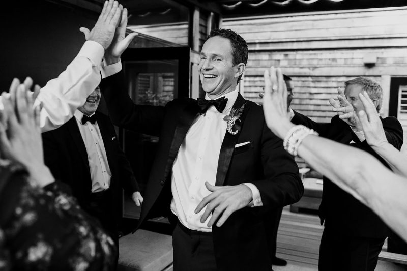 The groom high fives his friends during a destination wedding in Napa Valley California - powerful black and white wedding photography by ARJ Photography®