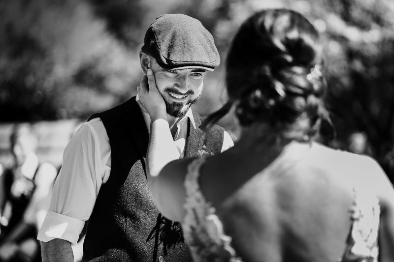 The bride touches the groom lovingly on the face during the wedding ceremony - powerful black and white wedding photography by ARJ Photography®