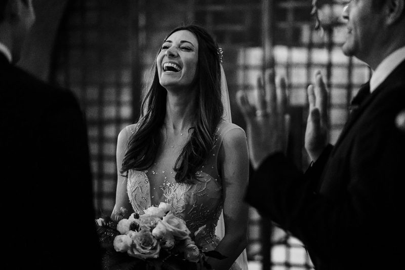The bride laughing during the wedding ceremony at a destination wedding in Napa Valley California - powerful black and white wedding photography by ARJ Photography®