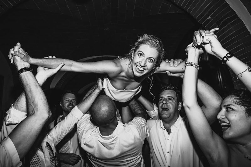 A bride crowd surfing during her wedding party at a destination wedding in Tuscany Italy - powerful black and white wedding photography by ARJ Photography®