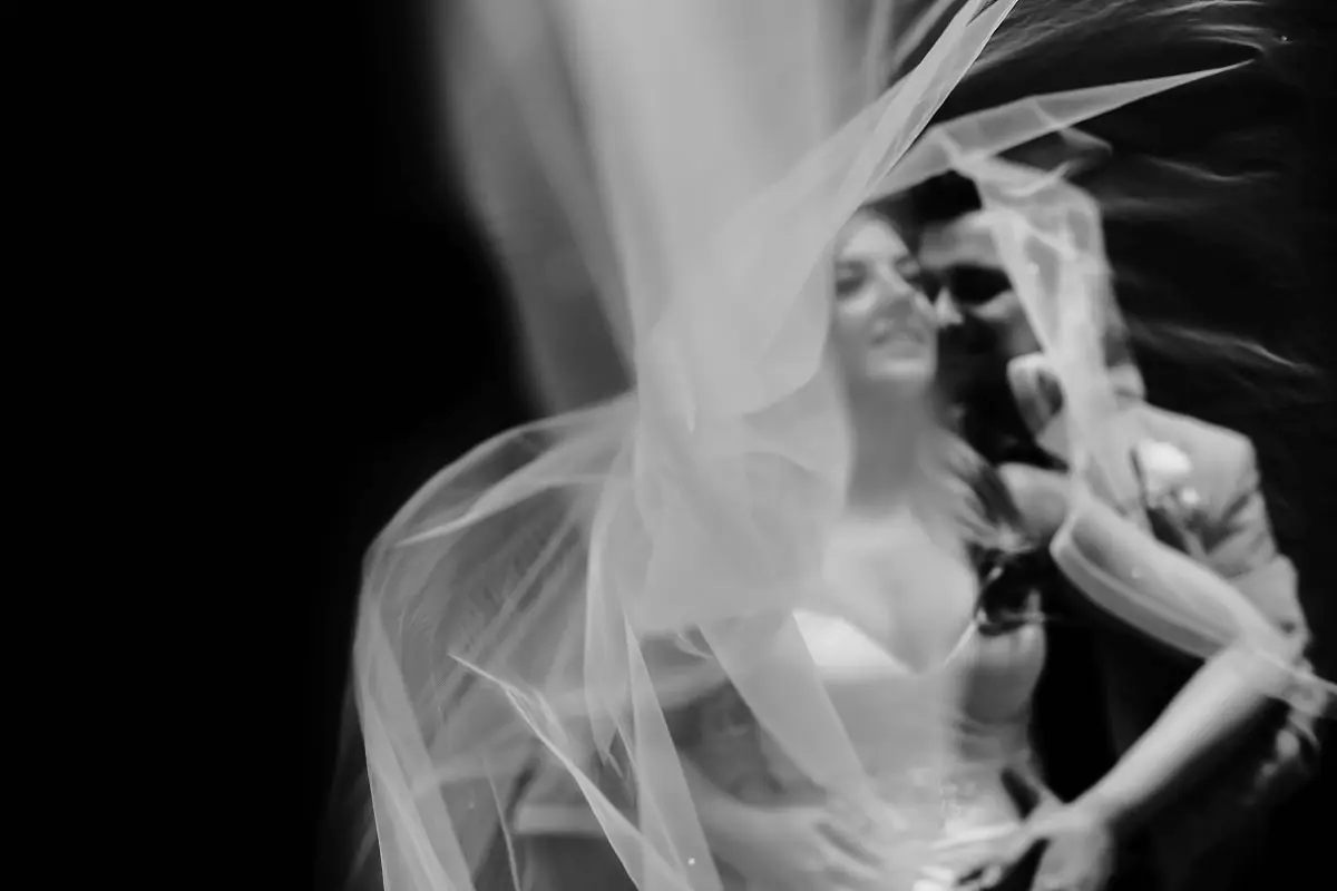 Amazing artistic black and white out of focus photo of a bride and groom with the veil of the wedding dress blowing in the wind - artistic wedding photography by ARJ Photography®