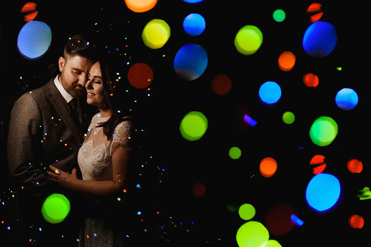 Christmas wedding photo of a bride and groom with abstract out of focus fairy lights - artistic wedding photography by ARJ Photography®