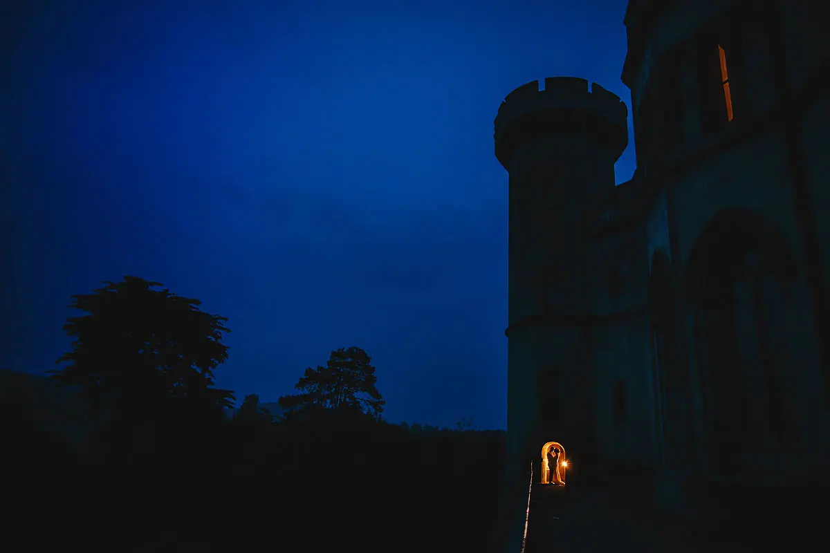 A bride and groom artistically framed in the doorway of their castle wedding venue - artistic wedding photography by ARJ Photography®