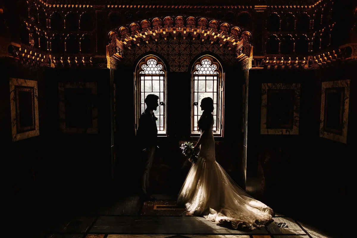 A semi silhouetted bride and groom framed perfectly by two windows during a wedding in Cardiff Castle - artistic wedding photography by ARJ Photography®