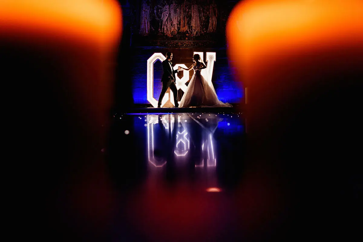 A colourful and unique artistic photo of a bride and groom dancing in front of massive letters of their initials at a castle wedding - artistic wedding photography by ARJ Photography®