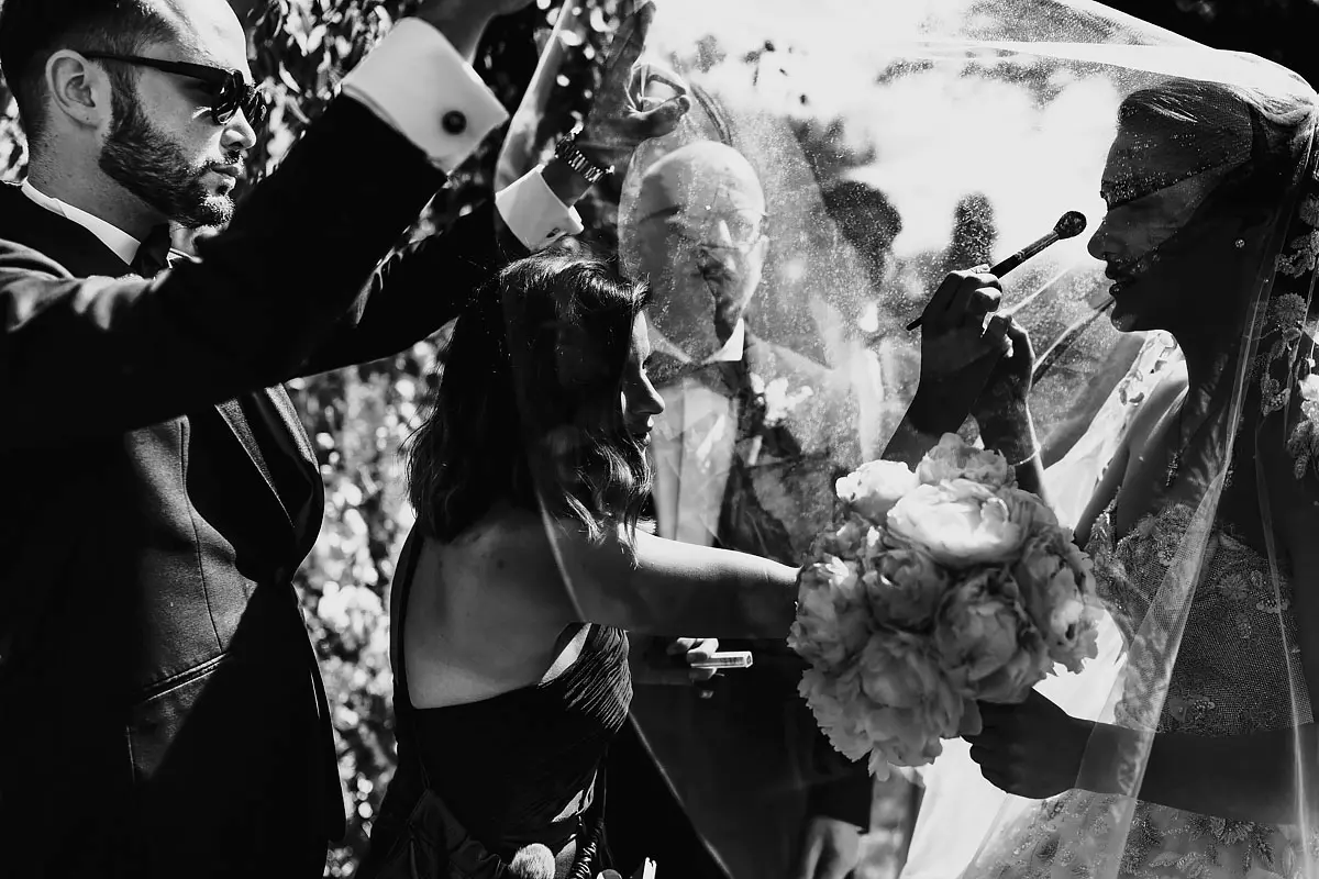 Artistic black and white photo of a bride having her makeup touched up during a destination wedding in Tuscany Italy - artistic wedding photography by ARJ Photography®