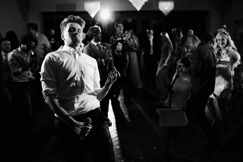 A groom playing air guitar in this black and white wedding photo - epic wedding party photo by ARJ Photography®