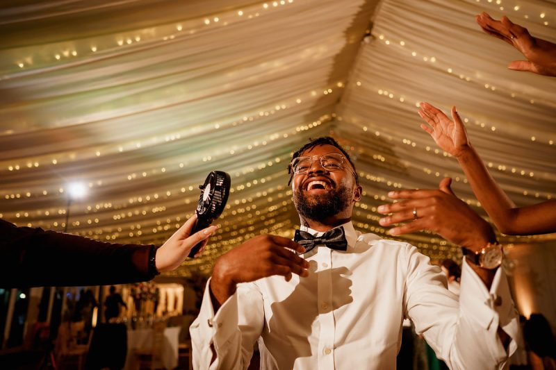 A groom being cooled down by guests on the wedding dance floor - epic wedding party photo by ARJ Photography®