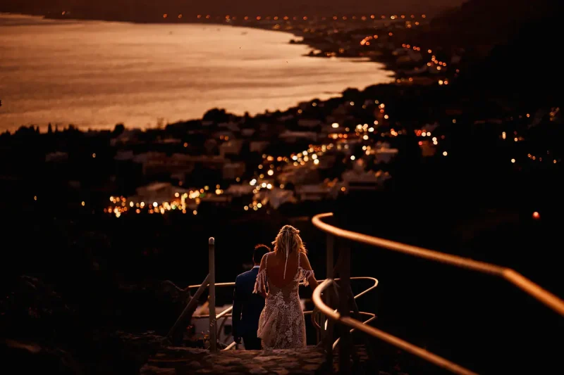 Bride and groom walking towards Pefkos town at a destination wedding in Rhodes Greece after sunset by destination wedding photographer ARJ Photography®