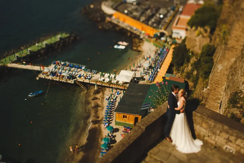 A bride and groom pose above the iconic piers of Sorrento Italy by destination wedding photographer ARJ Photography®