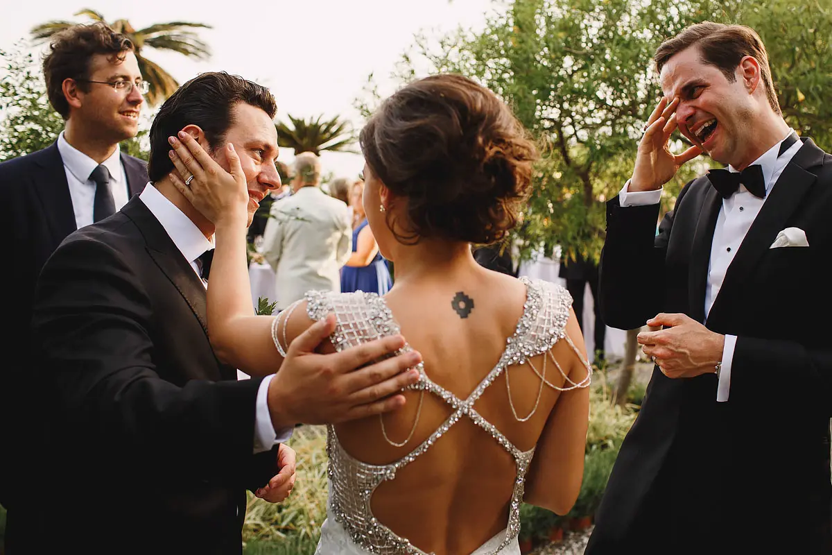 An emotional groom and best man are consoled by the bride at a wedding in Taormina Sicily by destination wedding photographer ARJ Photography®