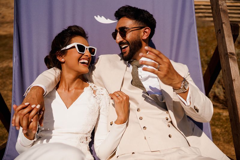 Bride and groom laughing together and wearing sunglasses at a summer wedding - incredible wedding portraits by ARJ Photography®