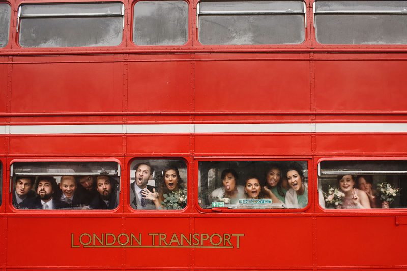 Wedding party portrait - a humorous portrait of the wedding party pulling funny faces in the windows of a London bus - incredible wedding portraits by ARJ Photography®