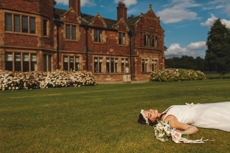 Quirky portrait of a bride lying on the grass at her wedding venue in Cheshire - incredible wedding portraits by ARJ Photography®