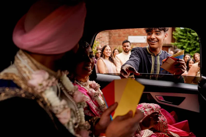 A brother tries to get paid during the bride and groom's exit from a Hindu wedding ceremony - Unique Indian wedding photos by ARJ Photography®